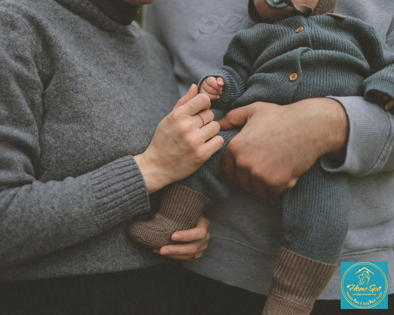 A supportive father gently cradling his newborn baby while the mother rests on the sofa, demonstrating shared childcare responsibilities, warm lighting, 1024x1024